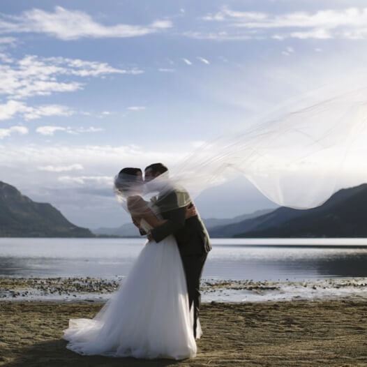 Сouple wearing a white gown and a black suit on the beach